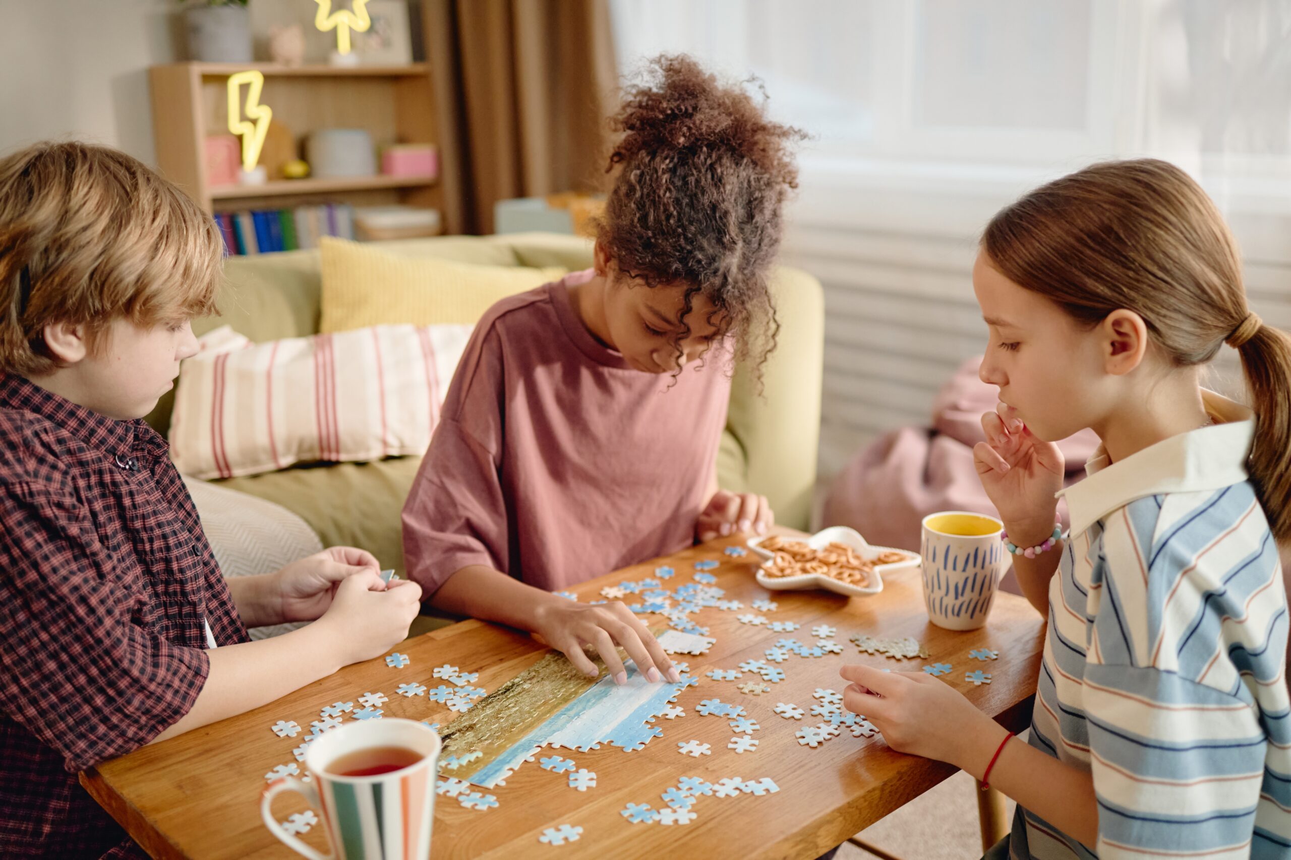 multiethnic,group,of,children,assembling,jigsaw,puzzle,on,wooden,table,