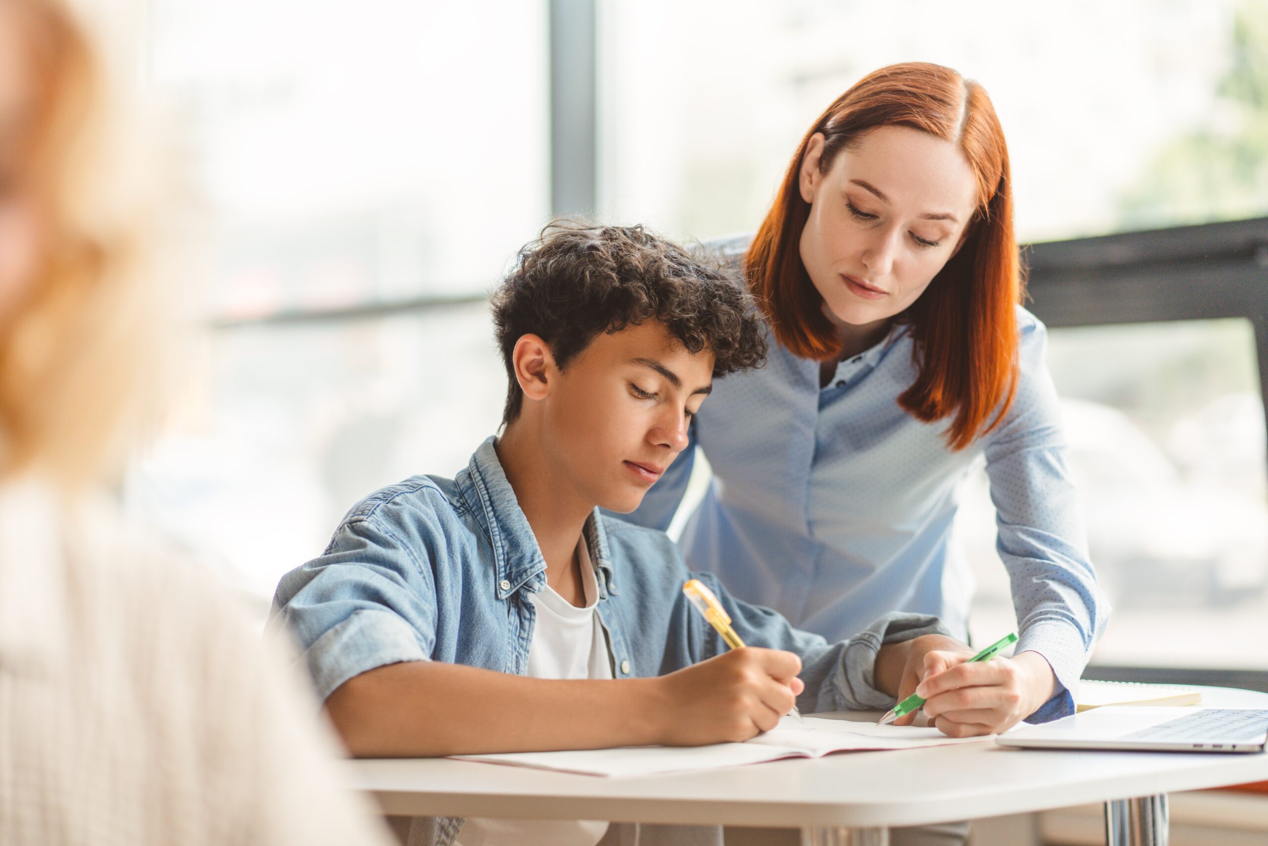 young,pensive,school,teacher,explaining,something,to,smart,teenager,,standing